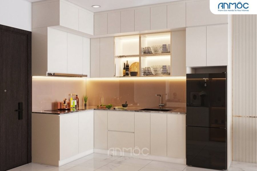 Khu vực bếp hình chữ L với tủ bếp trên và dưới màu trắng cùng với tủ lạnh âm màu đen và kệ mở có đèn chiếu sáng.
