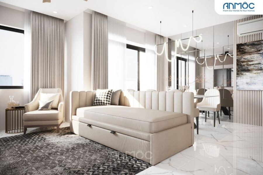 Góc phòng khách có sofa giường màu be, ghế đọc sách đơn, bàn trà nhỏ và thảm trải sàn họa tiết hình học, tạo không gian ấm cúng