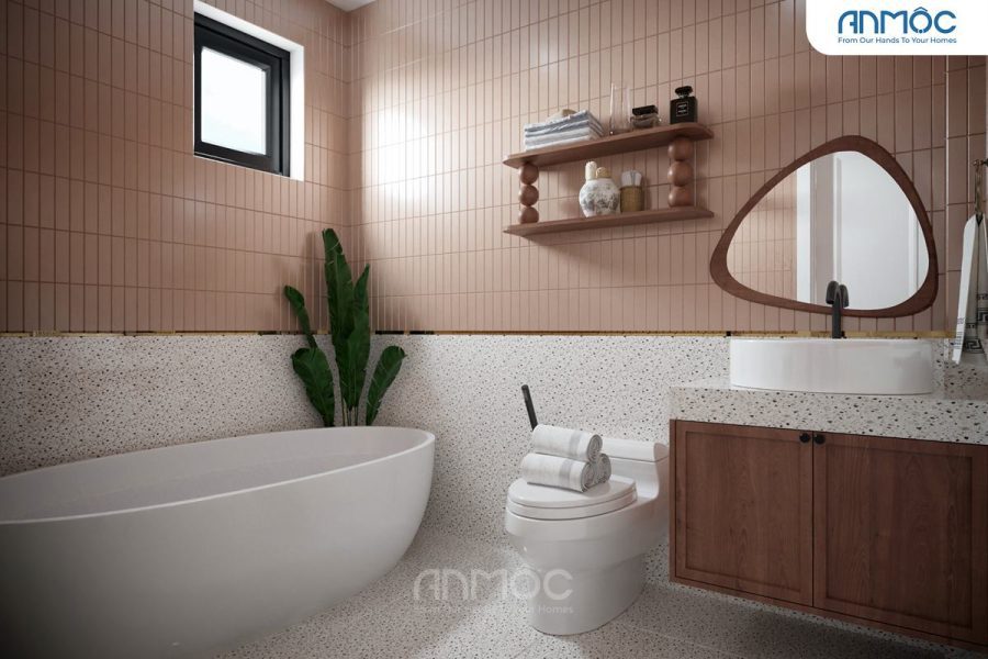 Phòng tắm master với bồn tắm độc lập màu trắng, tủ gỗ lavabo, gương hình hạt đậu và tường ốp gạch terrazzo kết hợp gạch hồng nhạt dọc