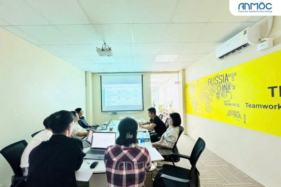 Phòng họp trang bị máy chiếu, màn hình lớn, và một bàn họp dài màu trắng với các ghế văn phòng màu đen