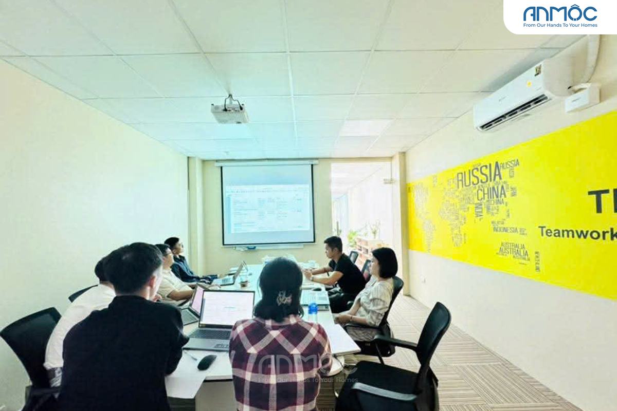 Phòng họp trang bị máy chiếu, màn hình lớn, và một bàn họp dài màu trắng với các ghế văn phòng màu đen