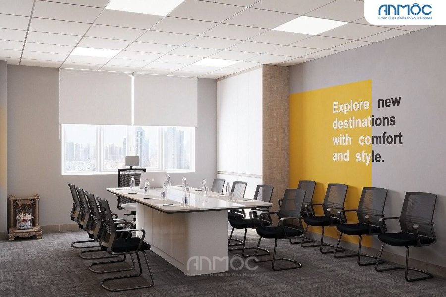 Bàn họp chữ nhật trắng lớn, ghế lưới đen và bức tường vàng với khẩu hiệu du lịch